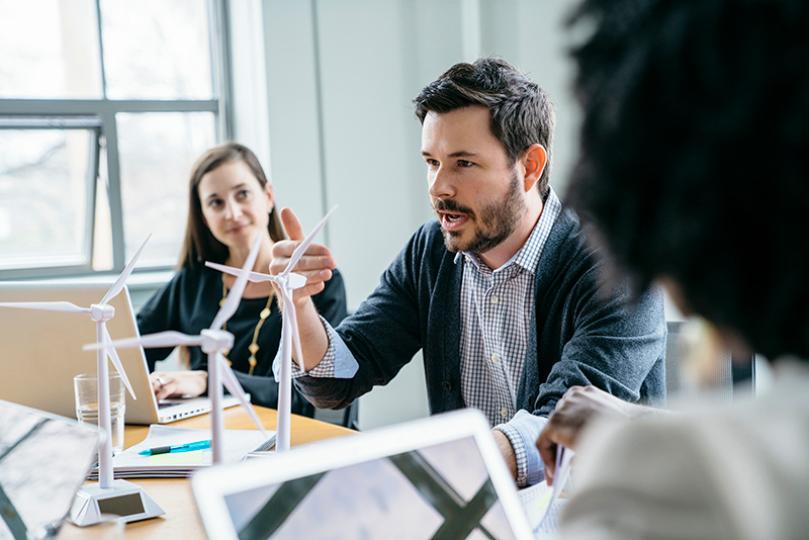 Businessman explaining wind turbine models to colleagues in office