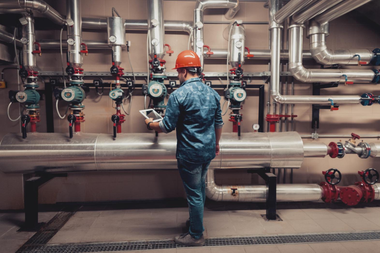 A man checks the readings on gas valves and piping. 