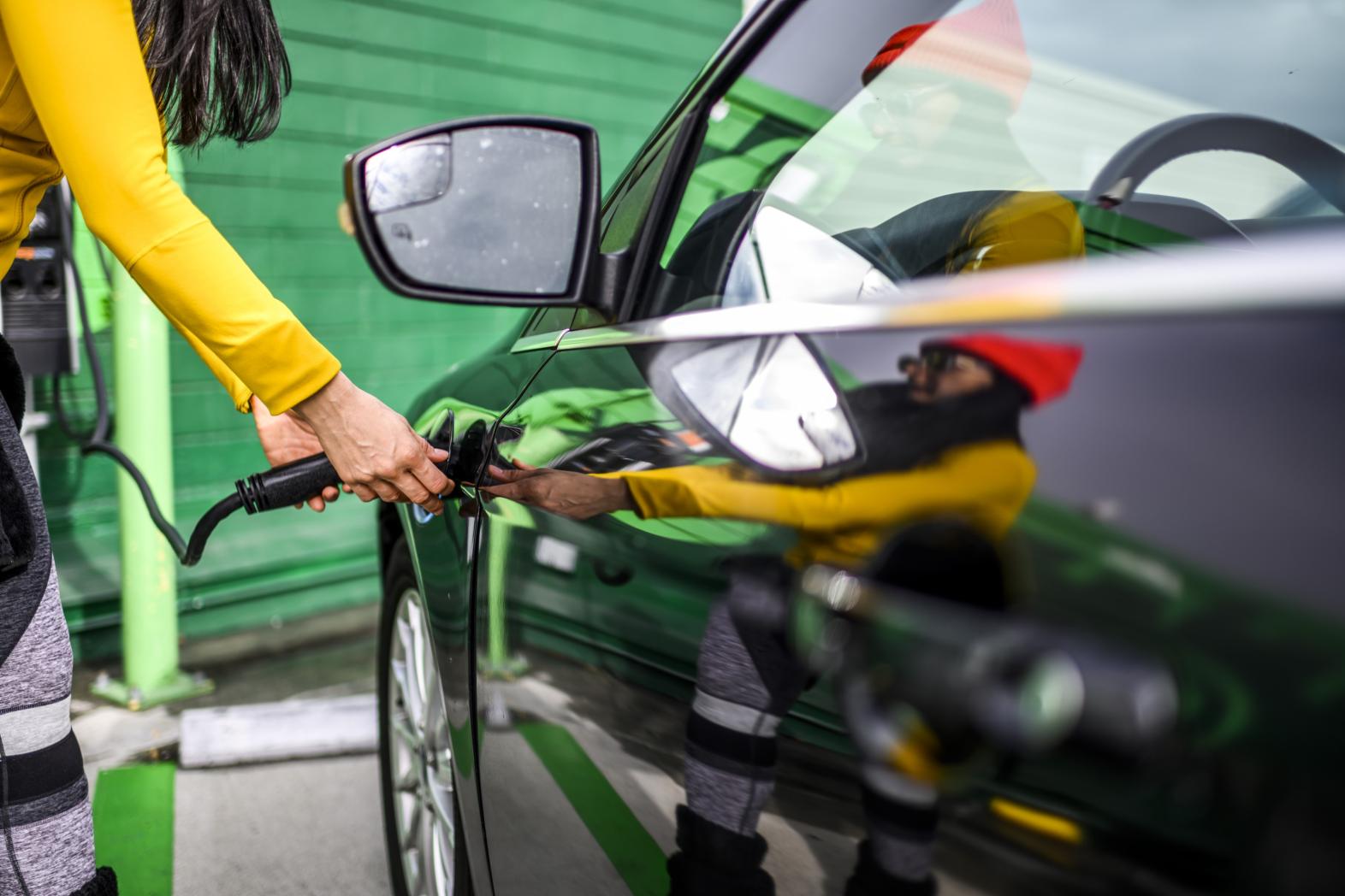 A woman charges an electric vehicle at a charging station