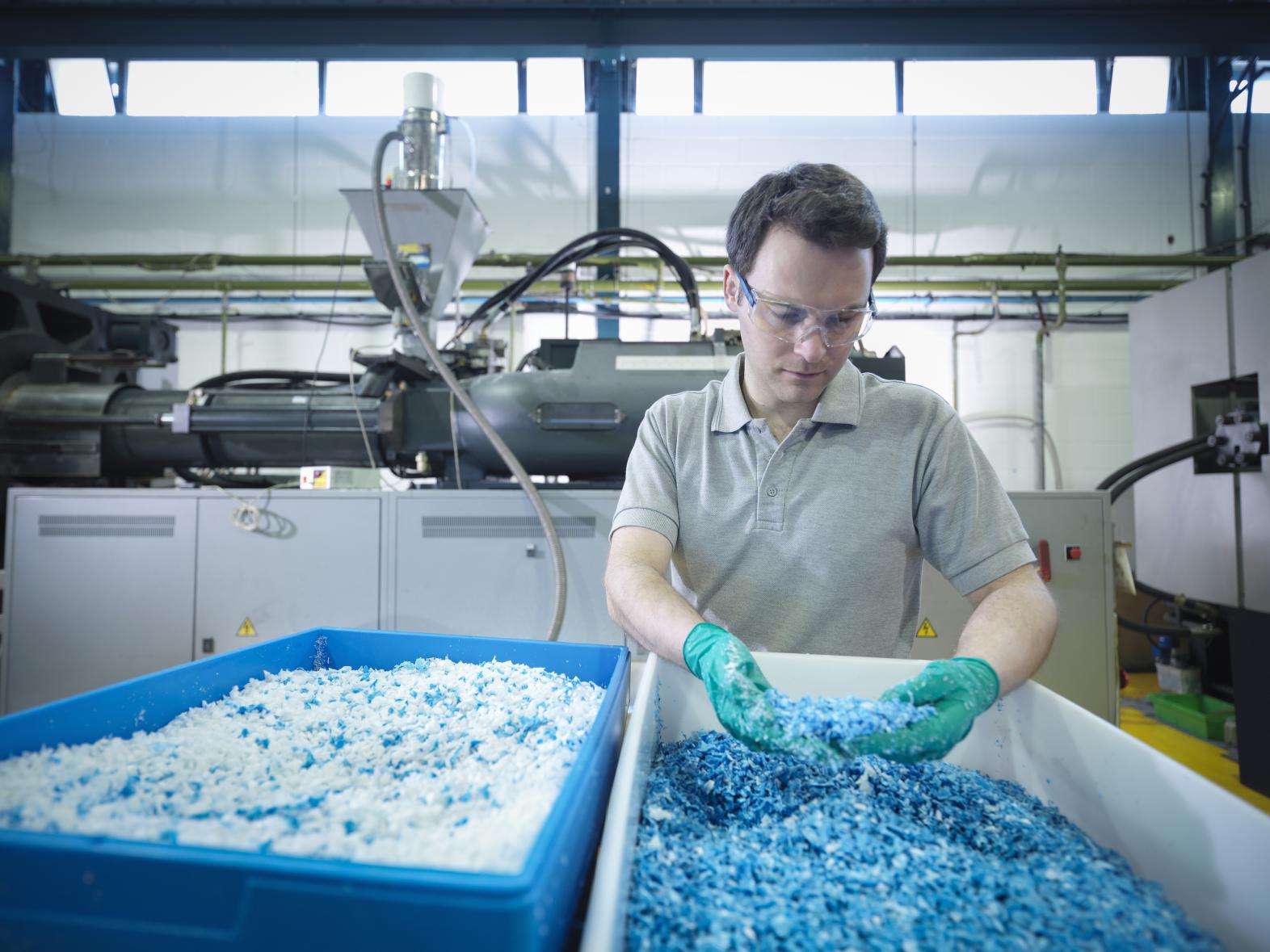 Man examining plastic pellets in a processing/recycling facility 