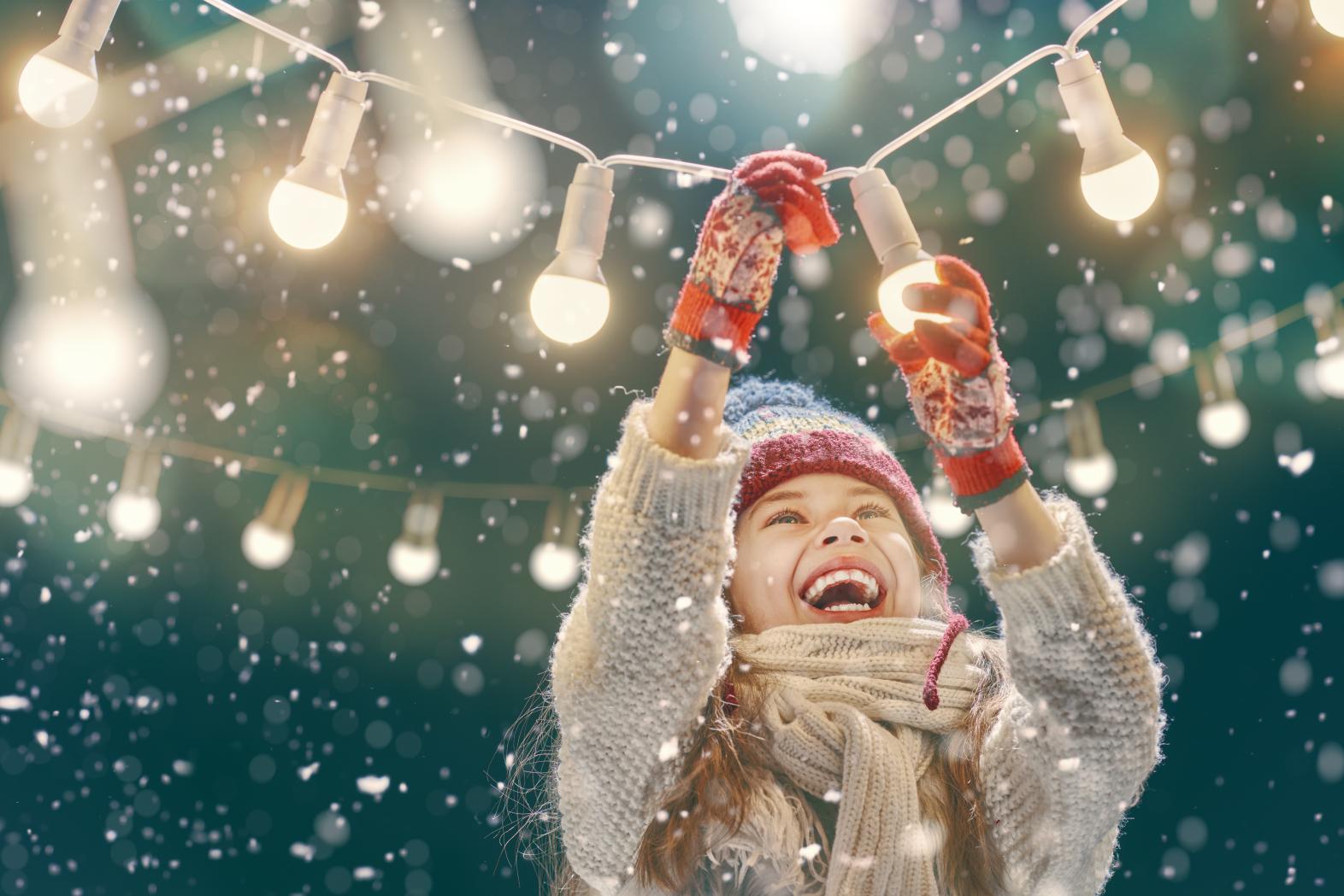 Happy Girl Hanging Christmas Lights in the Snow