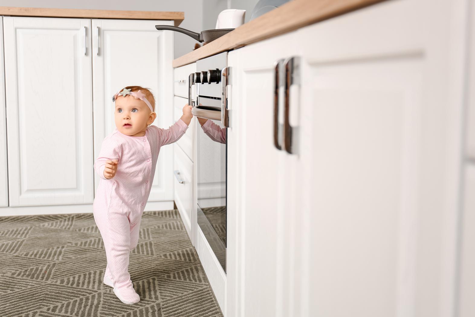 Baby standing near oven