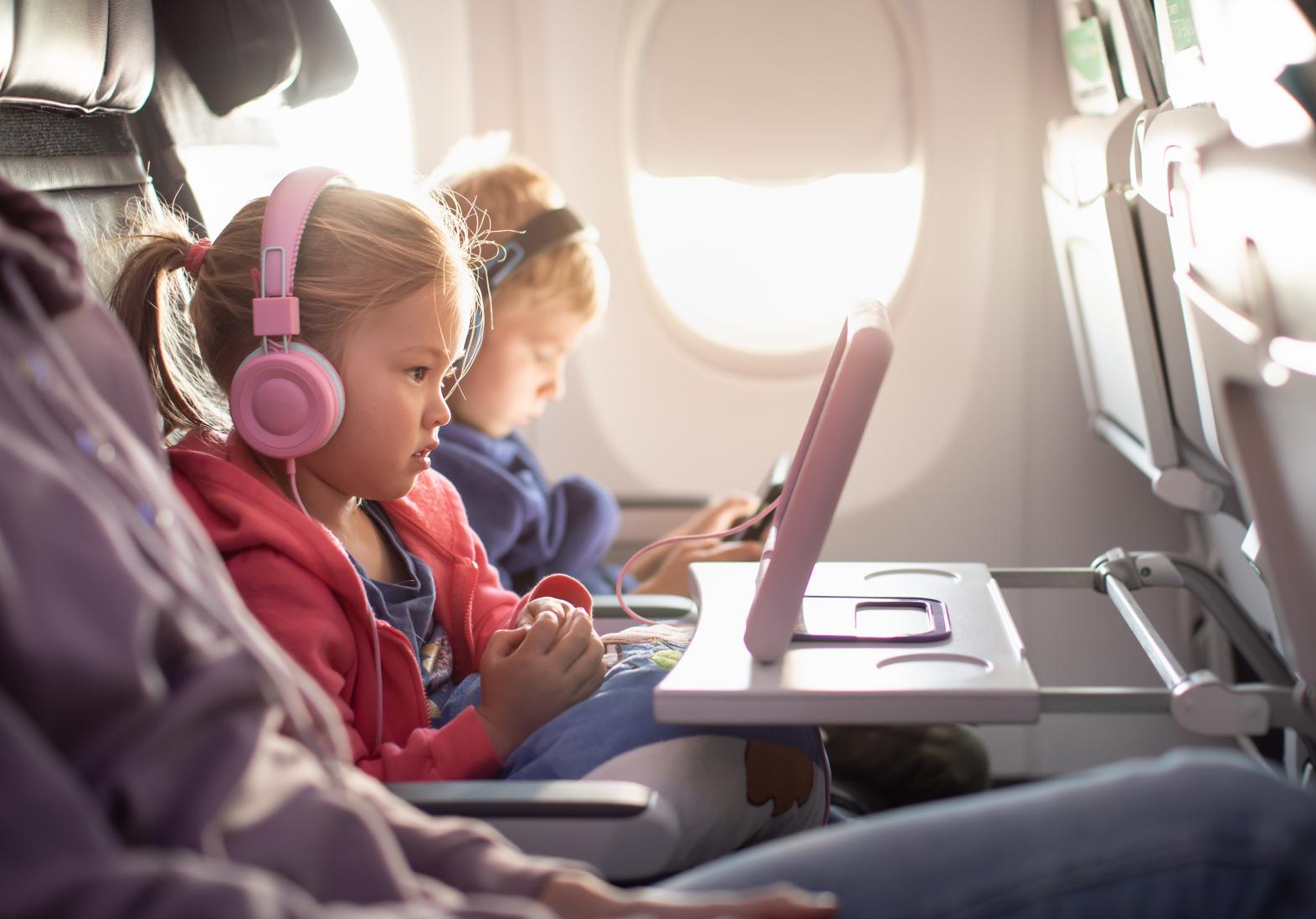 Little girl watching tablet with headphones on during a flight