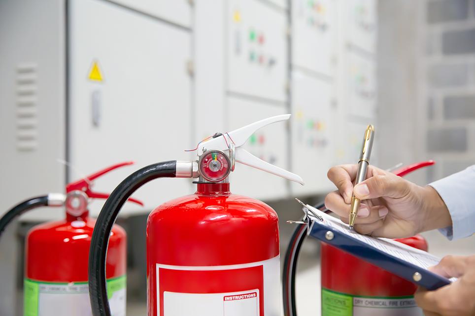 Person with clipboard inspecting fire extinguishers