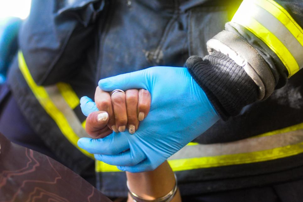 A firefighter holds a small woman's hand