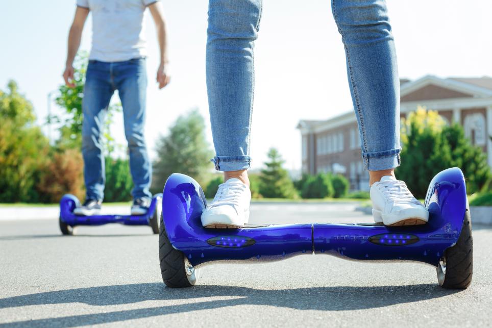 Youths riding hoverboard e-mobility devices outdoors on a nice summer day