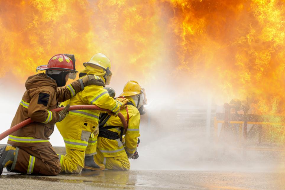 Firefighter training Firefighters using water and fire extinguishers to fight the flames in emergency situations. in a dangerous situation All firefighters wear firefighter uniforms for safety