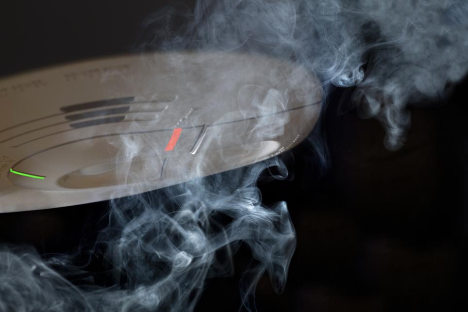 A smoke alarm is activated by smoke blowing toward it