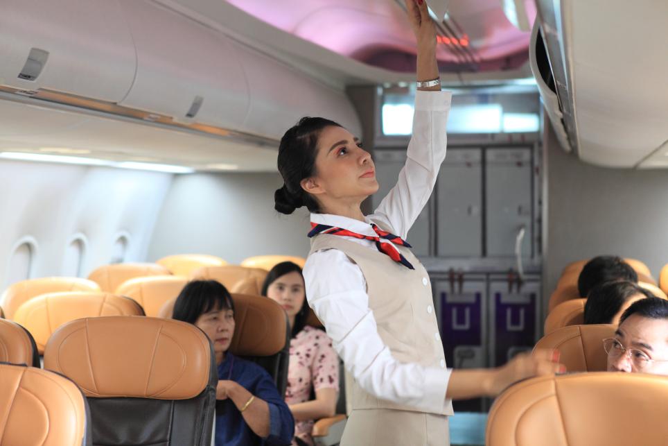 Cabin crew member loads luggage into overhead bin