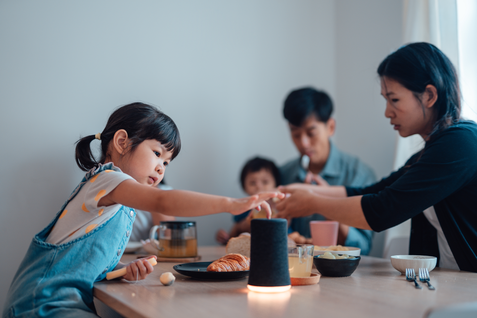 A family eats a meal with an activated smart speaker on the table