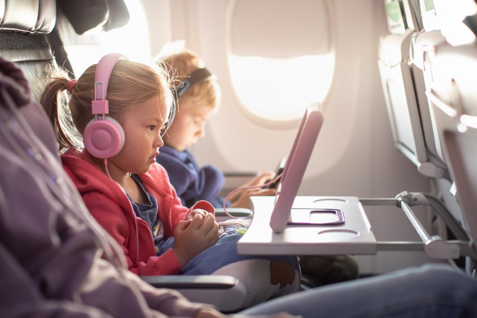 Little girl watching tablet with headphones on during a flight