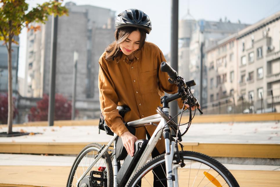 A young woman checks on her e-bike's battery before going out for a nice ride