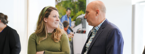 A woman in a green sweater and green headband talking to a man in a suit