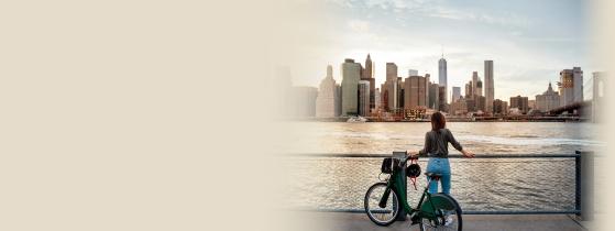 Woman standing with E-bike while looking at New York City Skyline