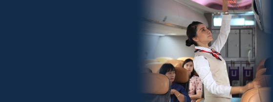 flight attendant loading luggage into overhead bin