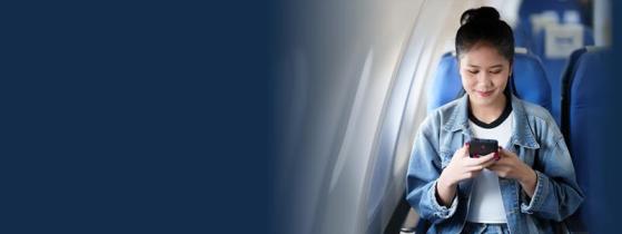 A woman on a plane smiling at a nice meme on her phone