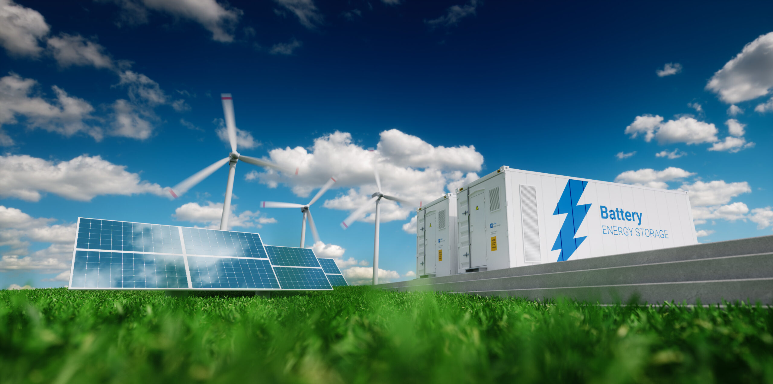 Solar panels, wind turbines, and battery storage units on green grass under a blue sky with scattered clouds, representing renewable energy and sustainable power technology.