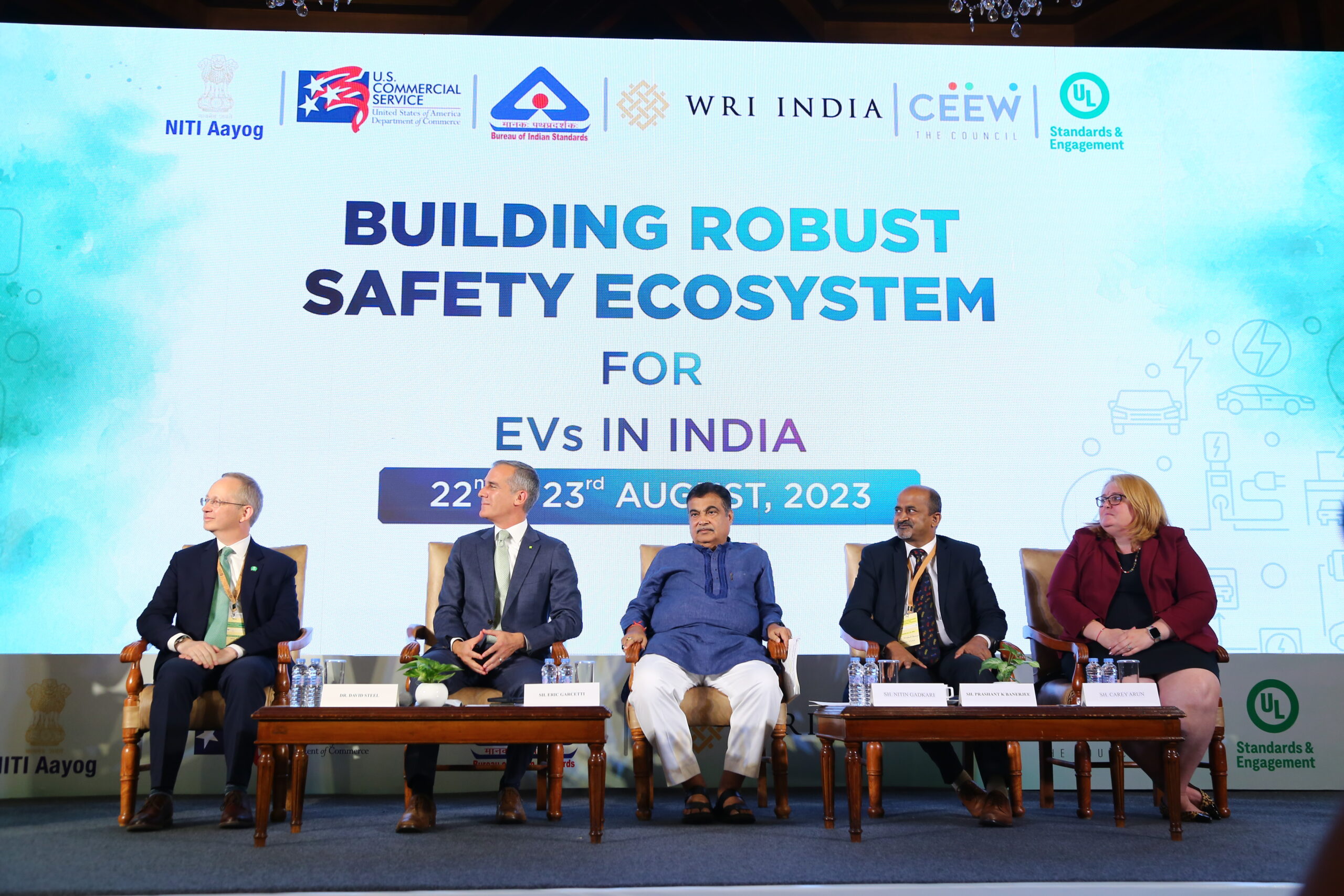 Five panelists sit on stage at a conference with a large screen behind them reading “Building Robust Safety Ecosystem for EVs in India, 22nd-23rd August, 2023,” surrounded by various sponsor logos.