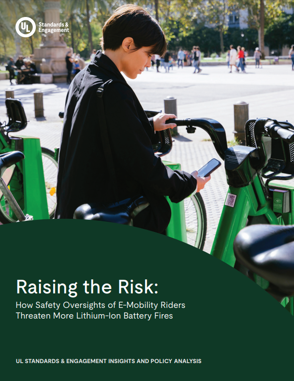 A person scans a QR code on a green e-bike parked at a bike-sharing station in an outdoor urban area. Title text reads, "Raising the Risk: How Safety Oversights of E-Mobility Riders Threaten More Lithium-Ion Battery Fires.