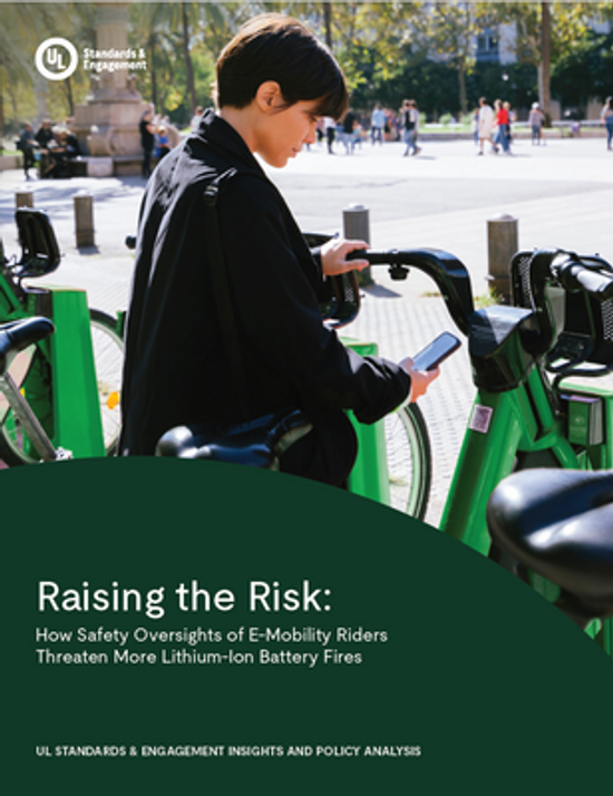 A person stands beside green electric bikes, looking at a smartphone. The image is overlaid with text about the risks of e-mobility riders and lithium-ion battery fires, from UL Standards & Engagement.