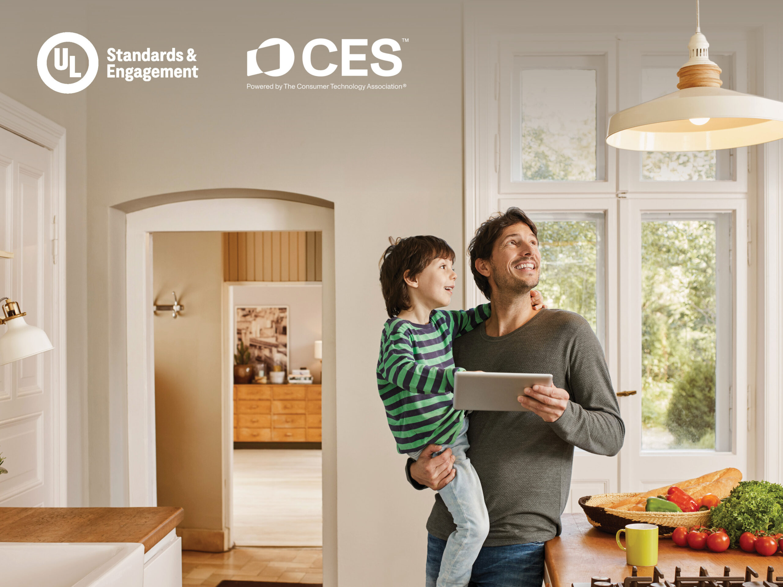A smiling man holds a tablet and a young boy in a bright kitchen with fresh vegetables on the counter. UL Standards & Engagement and CES logos appear in the top left corner.