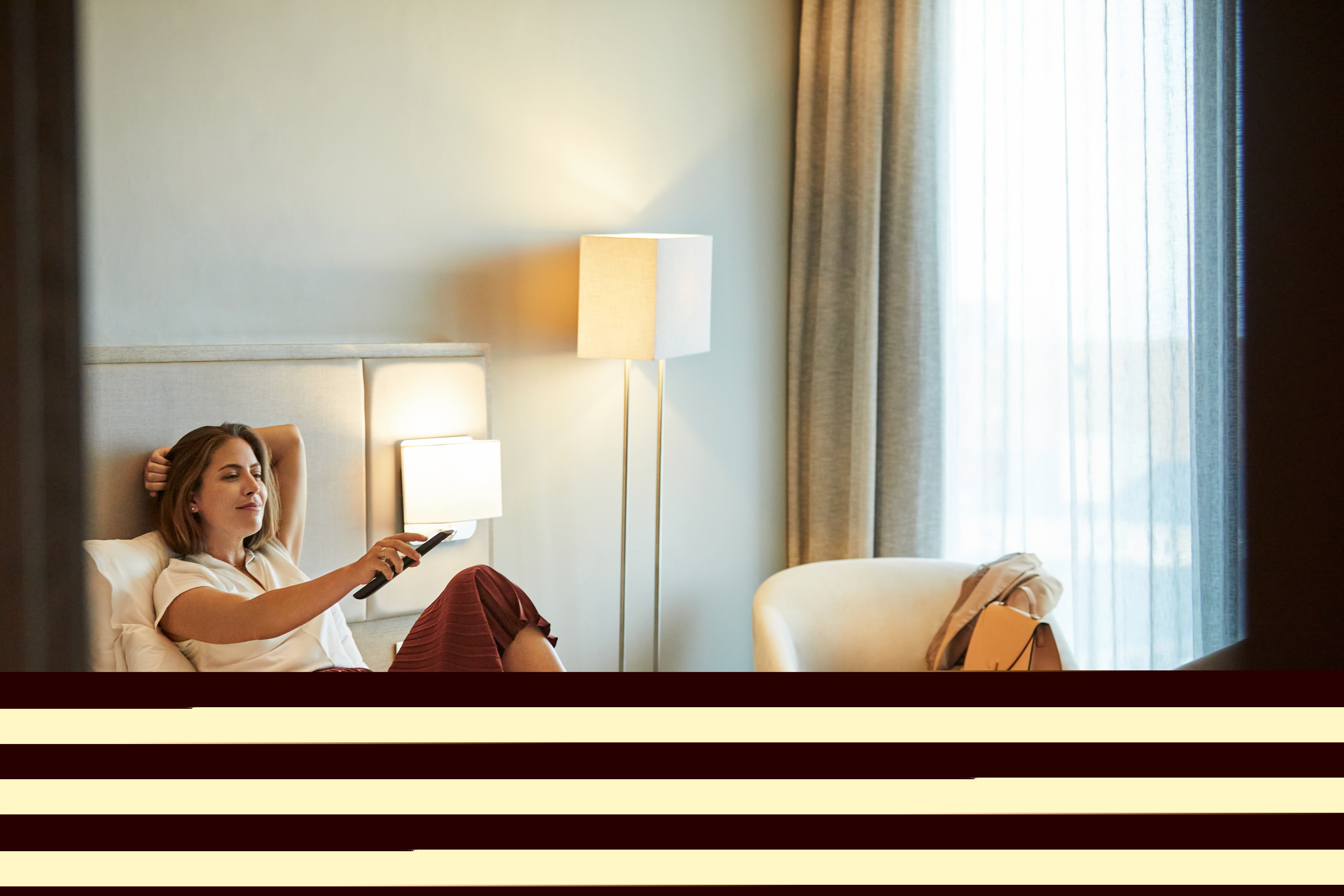 Woman reclining on bed in hotel room