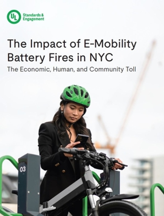 A woman in a green helmet stands next to an e-bike, looking at her phone. Behind her, construction cranes are visible. The text reads: "The Impact of E-Mobility Battery Fires in NYC. The Economic, Human, and Community Toll.