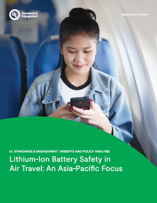 A woman sits on an airplane seat, smiling and using her smartphone. The text overlay reads: “Lithium-Ion Battery Safety in Air Travel: An Asia-Pacific Focus” by UL Standards & Engagement.
