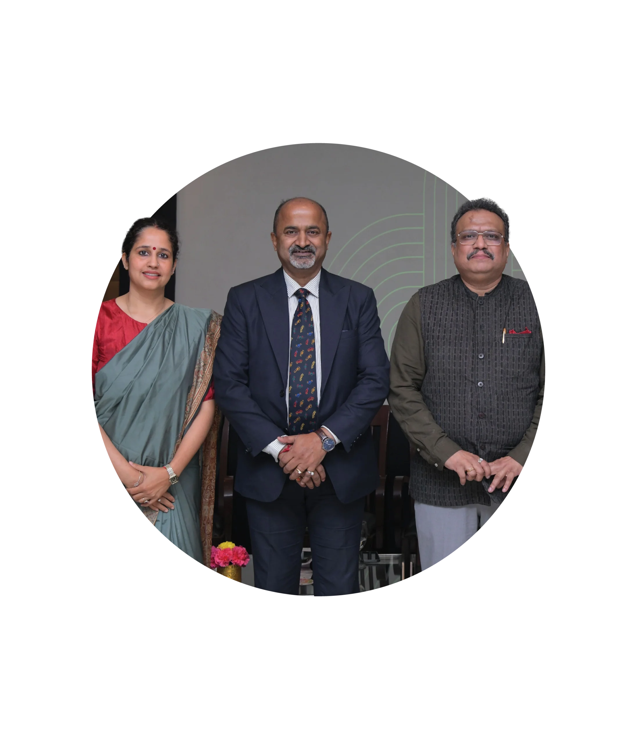 Three people stand together in formal attire—a woman in a green saree and two men in suits—posing for a group photo against a neutral background, representing their commitment to international safety partnerships.