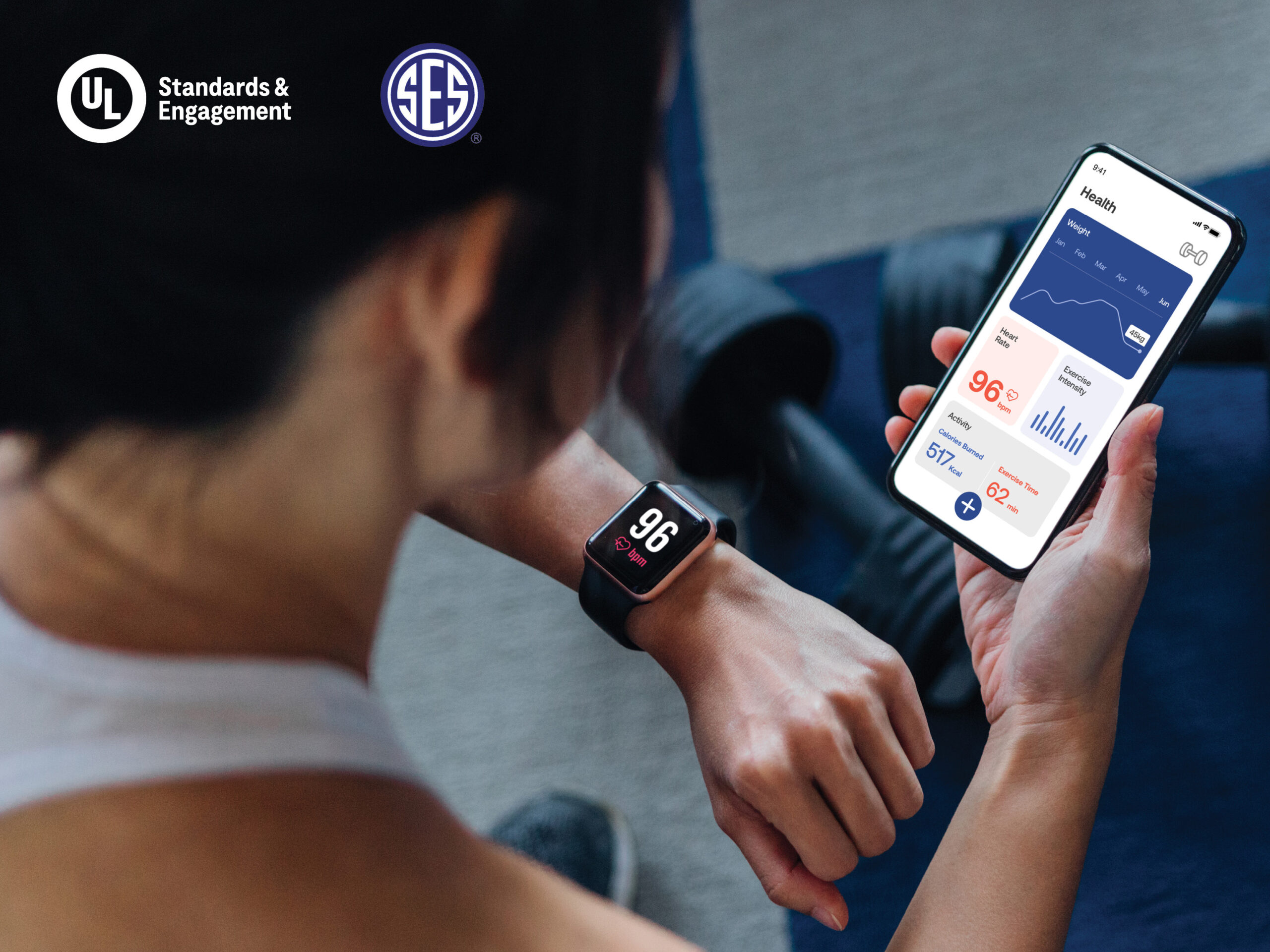 A person checks a fitness tracker on their wrist and holds a smartphone displaying health data. The UL Standards & Engagement and SES logos appear in the top left corner. Gym equipment is visible in the background.